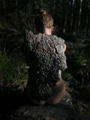 Hátulról fotózott női alak, hátán fakéreggel borítva, természetes környezetben, 2021.;